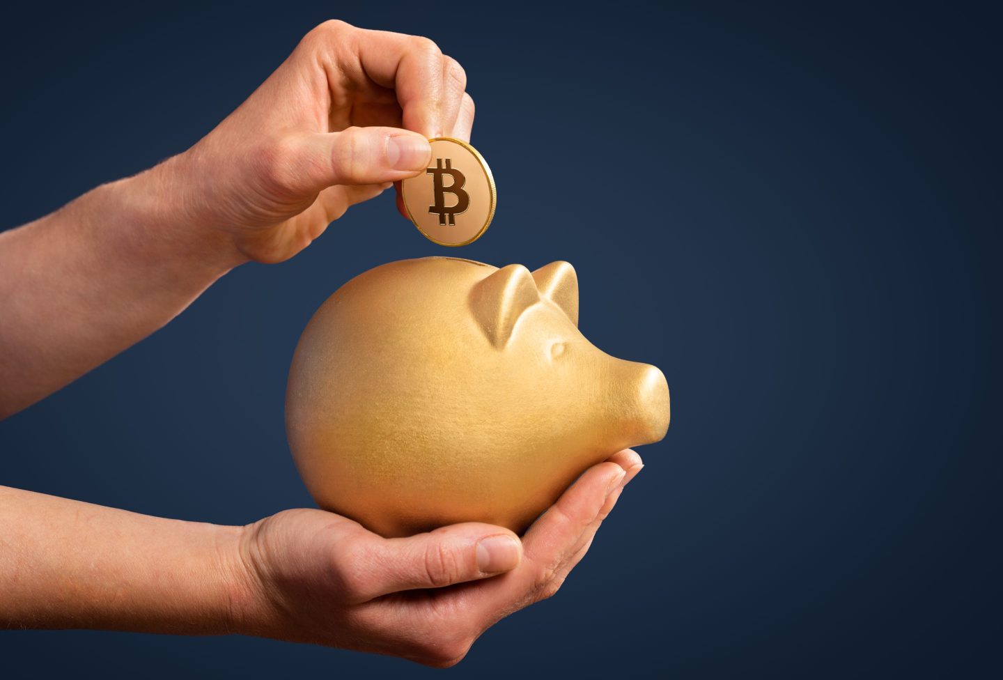 A person putting a Bitcoin into a gold piggy bank.